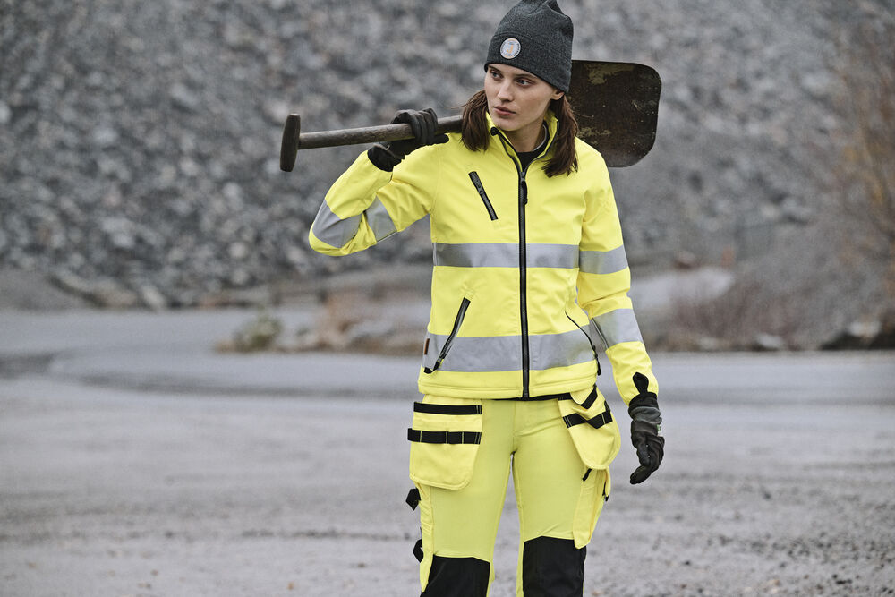 Anläggningsarbetare i varseljacka och varselbyxor med slägga