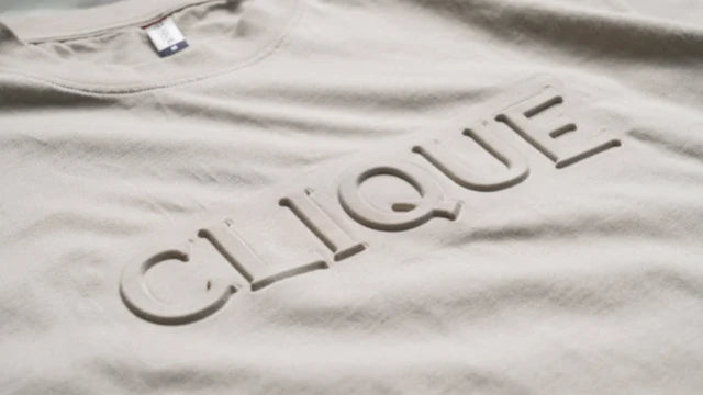 Beige t-shirt med ordet Clique präglat i relief i tyget