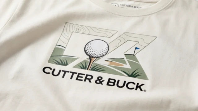 Vit t-shirt med ett detaljerat tryck i flera färger av en golfboll på en tee och texten Cutter & Buck