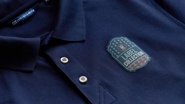 Mörkblå piké med ett märke i flera färger och texten Label Collection på bröstet