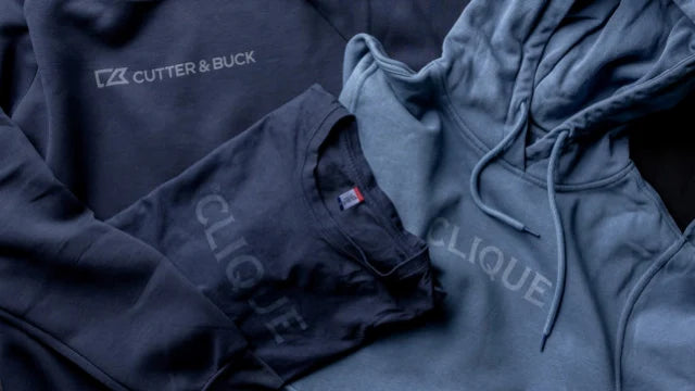Mörkblå t-shirt och hoodies med logotyper som syns i en ljusare ton av tygets färg