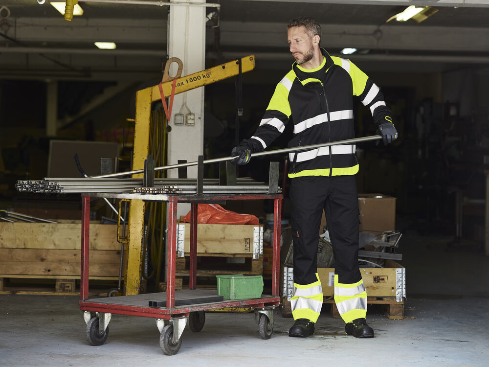 Lagerarbetare i varseljacka med vagn vid en lastport