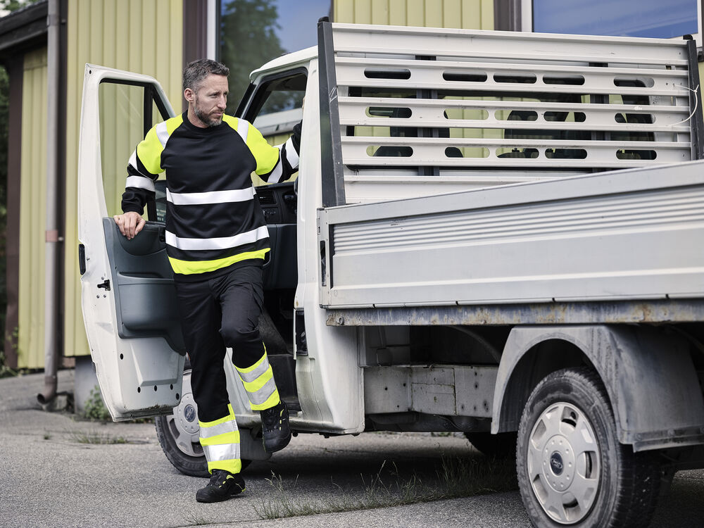 Förare i varselsweatshirt kliver ur en flakbil