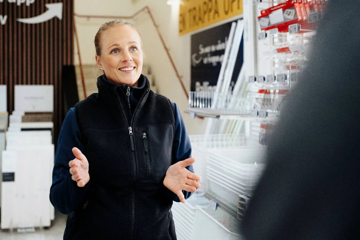 Kvinna i svart fleeceväst som förklarar något i en butik